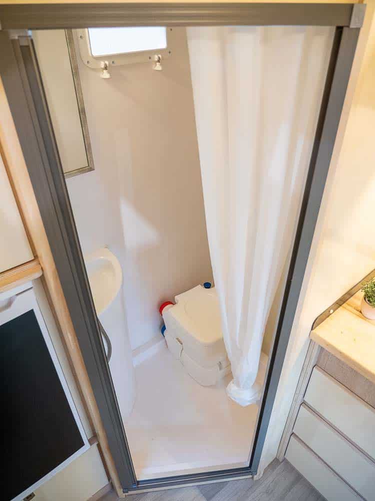 Blick ins Bad mit Waschbecken, portabler Kassettentoilette und Dusche.