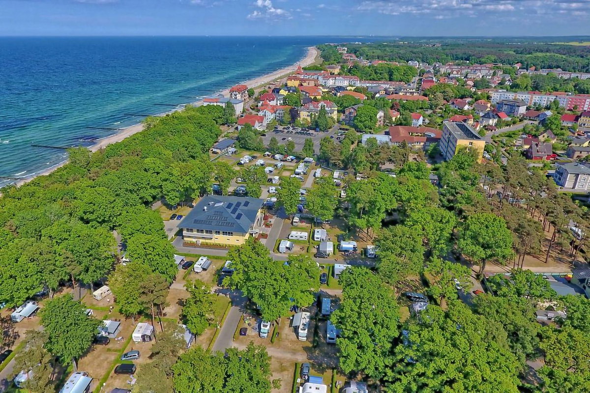 Camping.info Nr. 1 in Duitsland: Camping Kühlungsborn. Je ziet een luchtfoto van een camping op het platteland, met de zee op de achtergrond.
